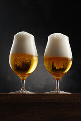 Two Glasses of golden beer on dark background.