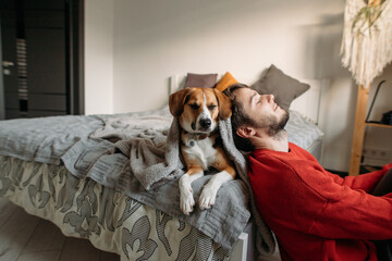 happy man with cute dog in bedroom on bed