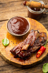 Delicious BBQ baby-back ribs with tangy sauce and a basting brush on wooden cutting board