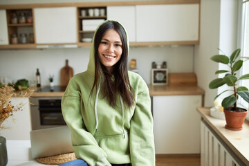 Communication, electronic gadgets and connection. Indoor image of joyful student girl in hooded...