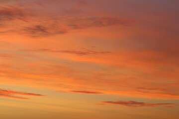 Sun below the horizon and clouds in the fiery dramatic orange sky at sunset or dawn backlit by the sun. Place for text and design