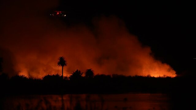 People watch massive fire burning at river bottom in Ventura, CA. People watch massive fire burning at river bottom in Ventura, CA.