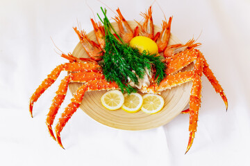 Red king crab and shrimp on a plate with lemon and dill. White background