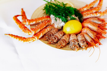 Red king crab and shrimp on a plate with lemon and dill. White background