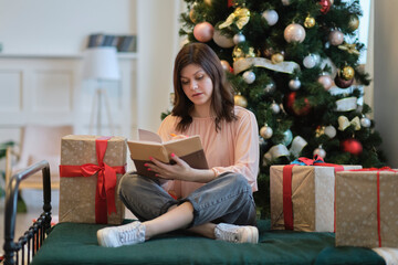 Photo of pretty young lady cuddle paper book. christmas holidays and people concept happy young woman with pencil and notebook writing in bed at home bedroom