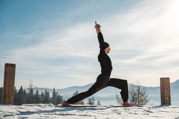Caucasian senior man doing yoga exercises in front of amazing sunset on the winter mountains. Copy, empty space for text