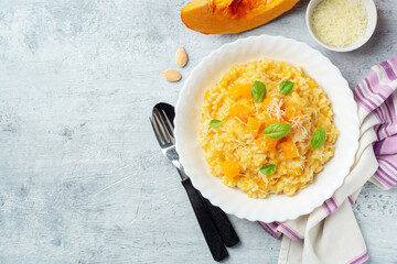 Pumpkin risotto with parmesan cheese and basil leaves on concrete background