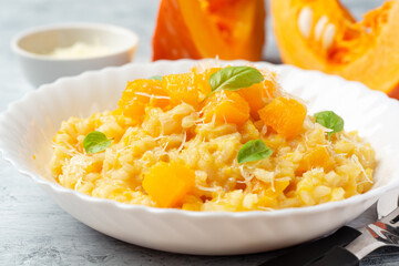 Pumpkin risotto with parmesan cheese and basil leaves on concrete background