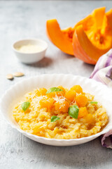 Pumpkin risotto with parmesan cheese and basil leaves on concrete background