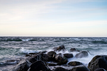 Fototapeta na wymiar Waves crashing into boulders, long exposure