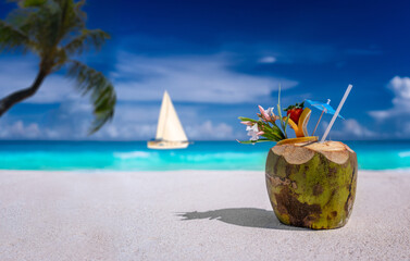 Coconut drink on a sandy beach with sailboat