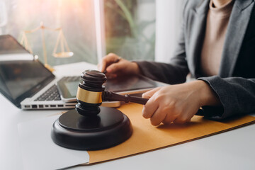 Fototapeta premium Justice and law concept.Male judge in a courtroom with the gavel, working with, computer and docking keyboard, eyeglasses, on table in morning light