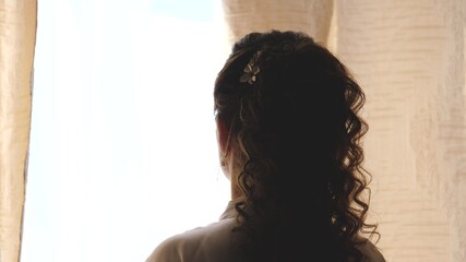 Hands pulling a window curtain for warm morning light. Slow motion. Young woman opening curtains in a bedroom. Closeup. Femele hands open window curtain in morning