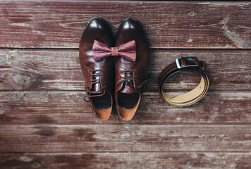 Close-up of leather brown shoes, with a strap, with a bow-tie on a wooden background. Gentleman's, men's set. Business. Wedding details. Photography, conception.