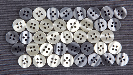 Plastic shiny buttons for clothes on a fabric background. Fashion and clothing. Factory industry