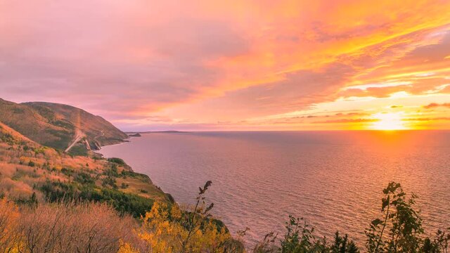 A timelapse of the Cap Rouge Mountains along the world famous Cabot Trail during an onset of a sunset with dramatic clouds overlooking the Atlantic Ocean and the highway. Shot in the autumn season wit