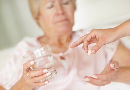 Nurse giving pill to senior woman - Powered by Adobe