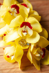 Naklejka na ściany i meble Wedding rings and yellow orchid on wooden backgraund