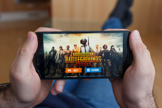 LOS ANGELES, CALIFORNIA - JUNE 3, 2019: Lying Man holding a smartphone and playing the PlayerUnknown s Battlegrounds PUBG game on the smartphone screen. An illustrative editorial image.