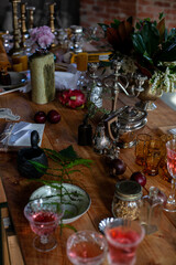 a variety of crystal glasses with rose wine, plates, candlesticks and other vintage staff in a mess on a wooden table