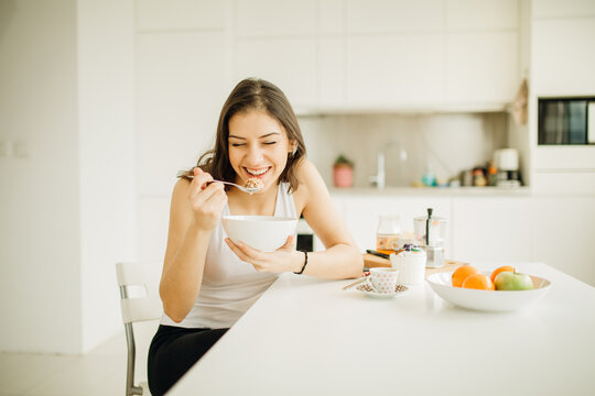 Young smiling woman eating cereal.Healthy breakfast.Starting your day.Dieting,fitness andmental health care.Positive energy and emotion.Productivity,happiness,enjoyment at home.Morning ritual