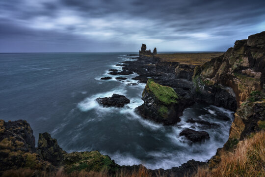 Magnificent scenery of rough cliff and calm sea under cloudy sky in long exposure in Iceland