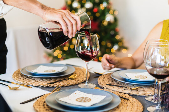 Crop view of hand of anonymous old man serving red wine during Christmas dinner