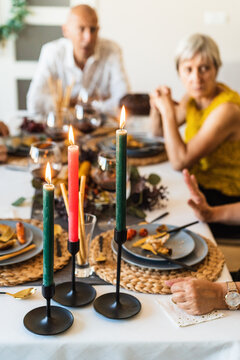 Bright wax candles with shiny flame on table during festive event on blurred background with bokeh effect