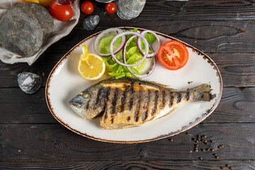 Grilled dorada with salad, onions and tomatoes. Classic hot fish dish of sea fish, vegetables and...