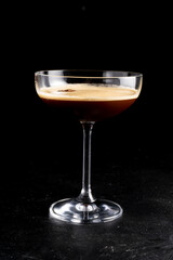 Espresso martini. Alcoholic cocktail of vanilla syrup, coffee liqueur, vodka and coffee beans in a transparent glass on a black background.