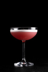 Clover club cocktail. Cold alcoholic cocktail of quail egg protein, lime juice, raspberry syrup and gin in a transparent glass on a black background.