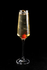 Cocktail French 75. Cold alcoholic cocktail of lemon juice, sugar syrup, gin and ice in a transparent glass on a black background.