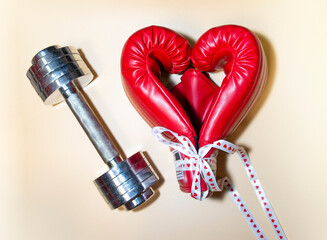 Gym background and fitness equipment and valentine concept. Boxing glove in shape of heart near the weights.