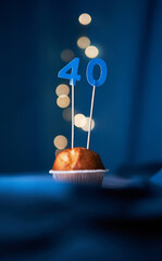 Birthday cupcake or muffin with forty (40) number and lights on the blue background. Birthday or anniversary concept