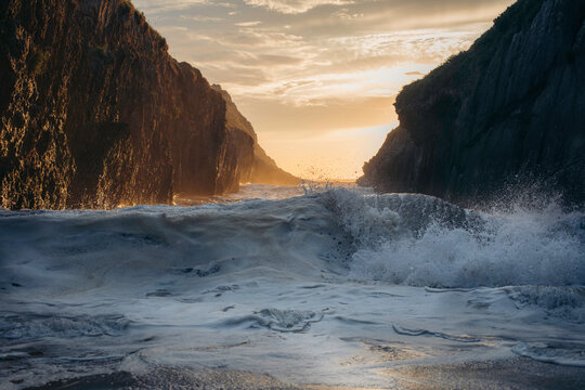 Powerful blue breaking ocean waves with white foam on sunset background