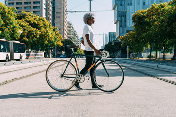 Black and afro man carrying and transporting his city bike in the city. Concept of cycling in the city. City bike.