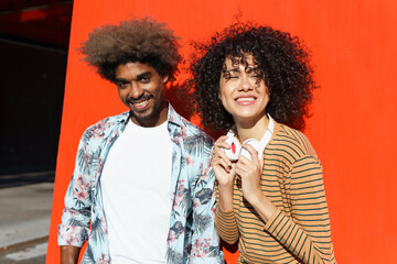 Stylish African American male with Afro hairstyle standing near cheerful female friend on street
