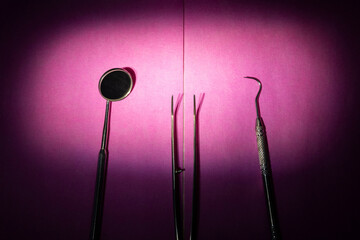 From above of various dental instruments arranged in row on pink table in clinic