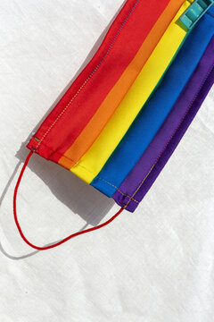 From above of detail of vivid protective mask with picture of rainbow flag placed on bed at home