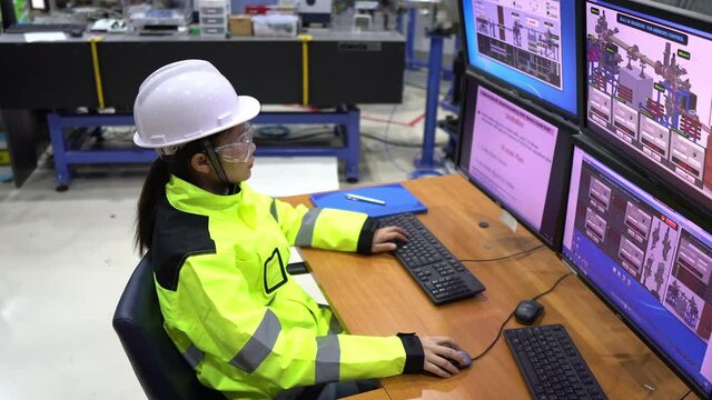 Inside the large Industry Factory Female Computer Engineer Works on Personal Computer She coding program for control machine,Thailand people work on fours monitors,Programmer working with serious