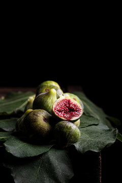 From above of fresh sweet figs arranged on green leaves on black table
