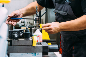 Crop anonymous workman in uniform working on drilling machine in modern industrial manufacture