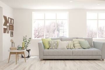 Fototapeta premium White living room with sofa and winter landscape in window. Scandinavian interior design. 3D illustration