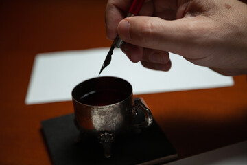 Hand dips fountain pen in inkwell