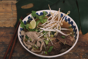 High angle of delicious Pho soup with beef and bean sprouts garnished with fresh parsley and green onions