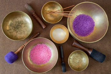 Tibetan singing bowls  with healing salt and 
aroma sticks on the cloth background - music instruments for meditation, relaxation, yoga, massage, sound healing