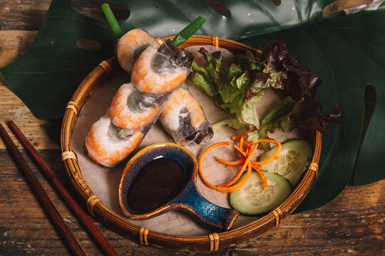 High angle composition of Vietnamese prawn rolls wrapped in rice paper and served on tray with barbecue sauce and lettuce leaves