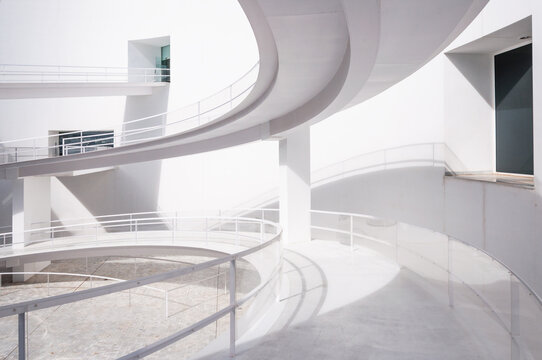 White smooth ramps or inclines with railings located outside modern futuristic building in sunlight