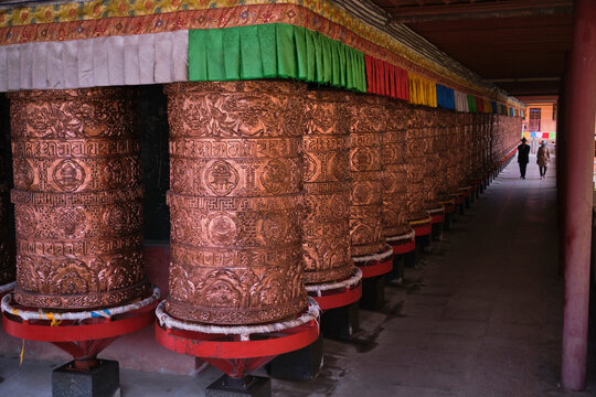 Tourists in traditional authentic Buddhist temple for worship with mantras on prayer wheels in Tibetan Buddhist temple