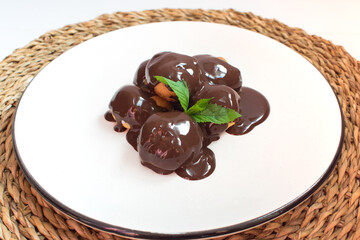 Chocolate profiteroles on a white plate.